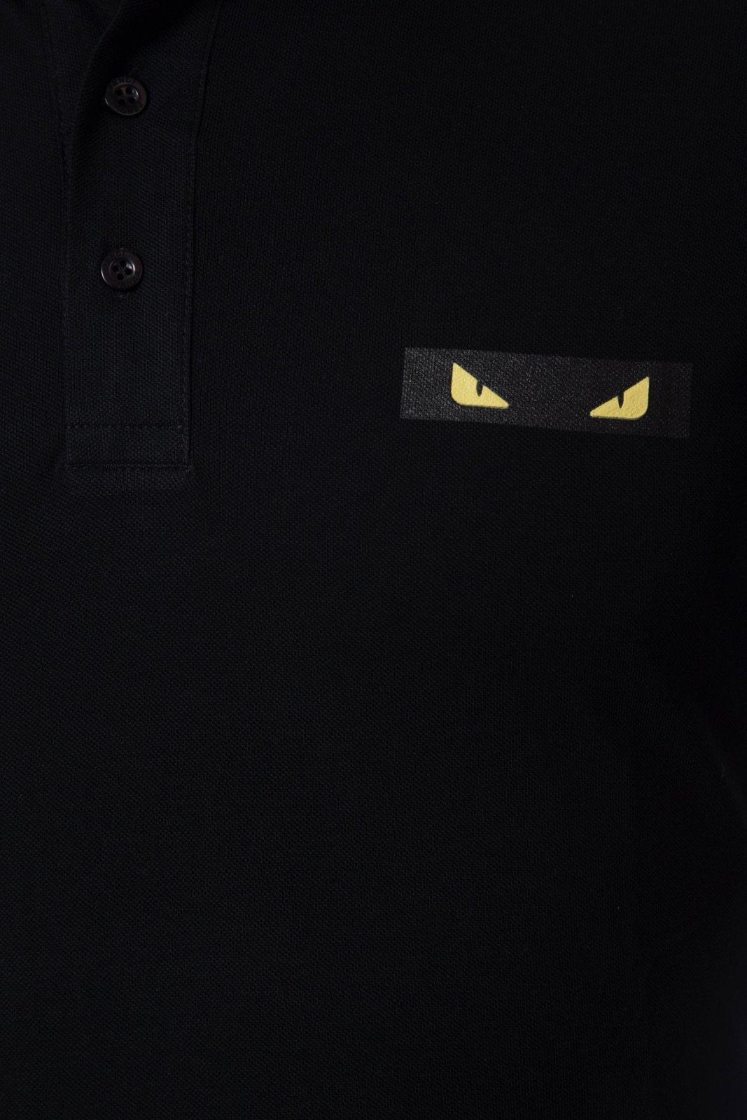 Close-up of black polo shirt with yellow eyes graphic on chest and black buttons